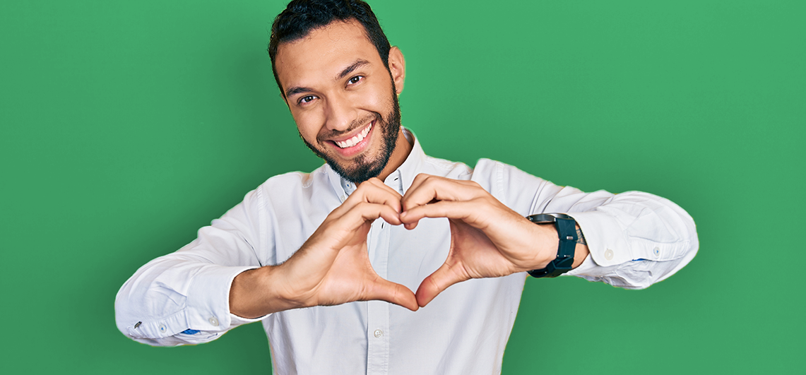 man making a heart shape with his hands and smiling
